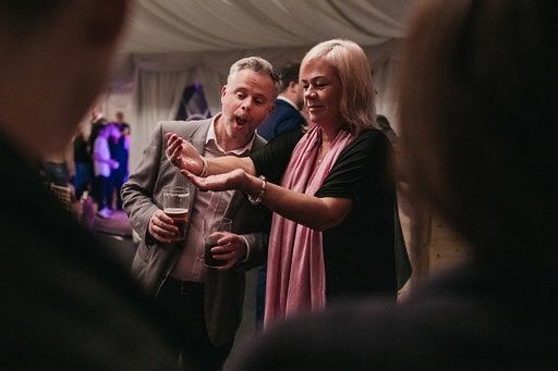 Man and woman reacting in amazement as Greg Holroyd performs a close-up hand magic trick at a corporate event