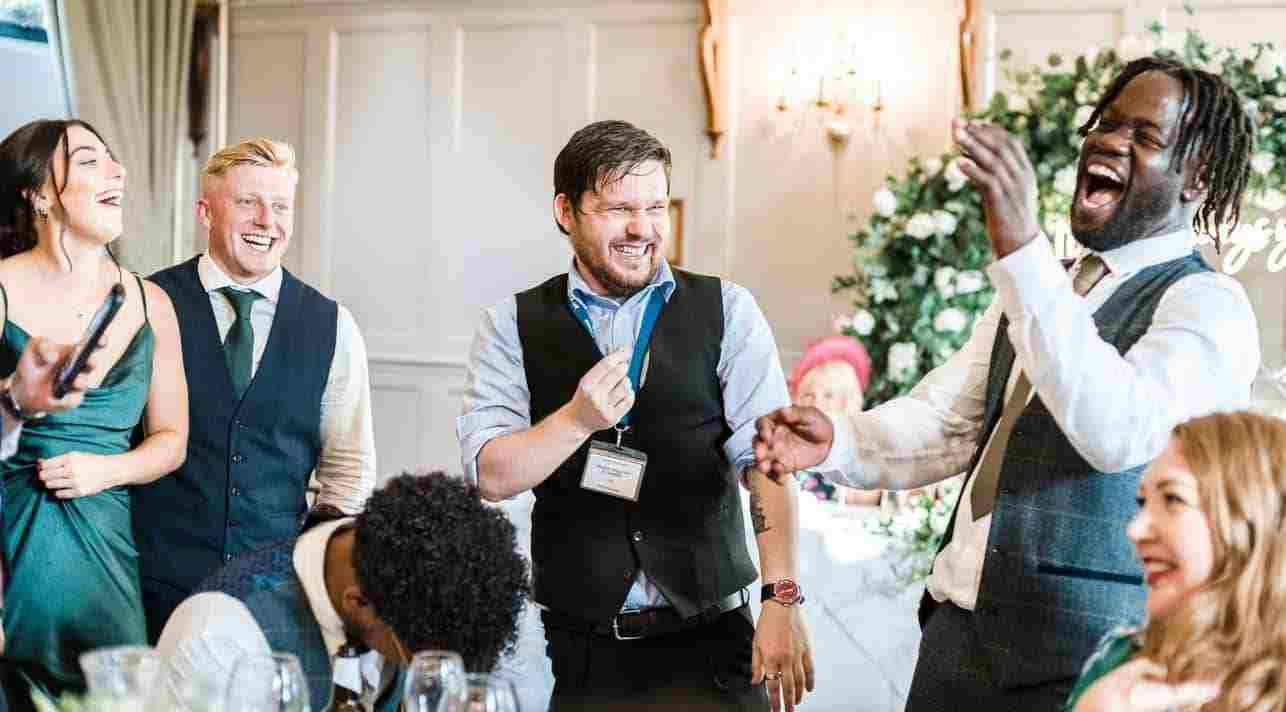 Wedding guests laughing during Greg Holroyd’s magic performance in Bedfordshire.