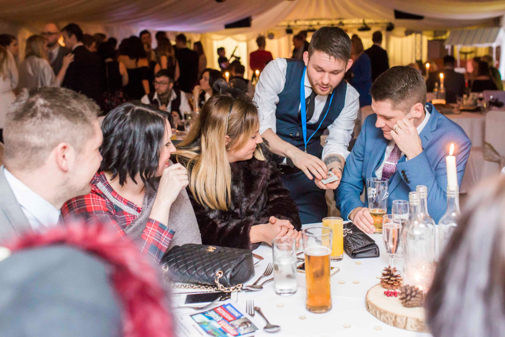 Greg Holroyd performing close-up card magic for guests at a corporate conference