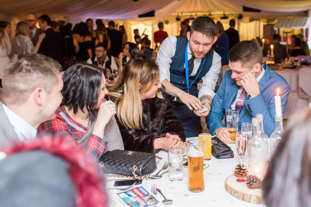 Corporate guests watching close-up magic during an awards evening