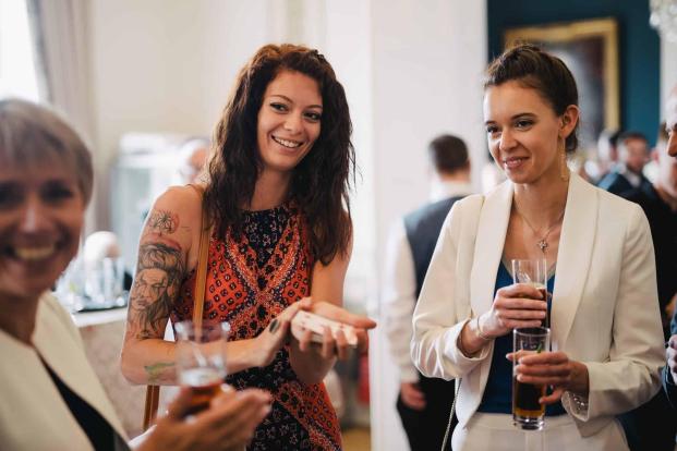 Wedding guests laughing as magician Greg Holroyd surprises them with a jaw-dropping card reveal during a Bedfordshire reception.