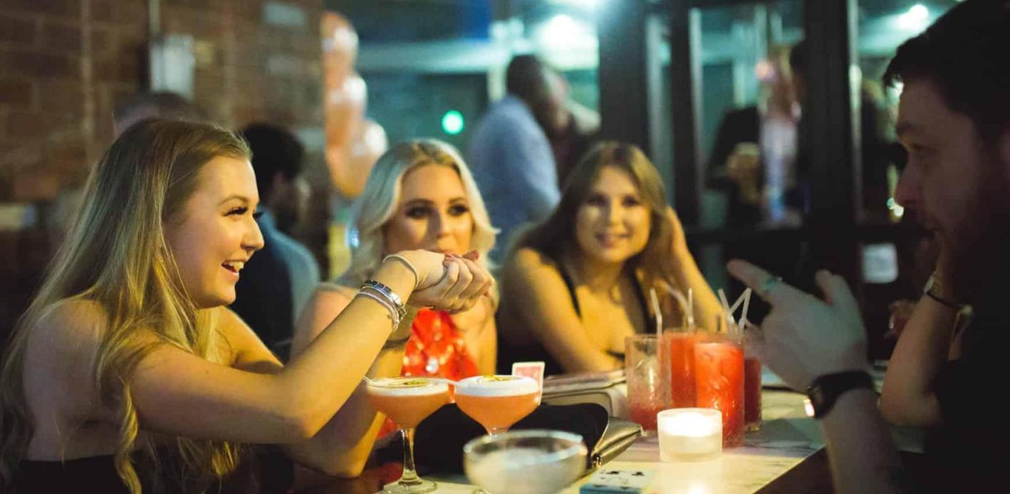 Greg Holroyd performing close-up magic at OHM Sheffield, making guests laugh during a cocktail event.