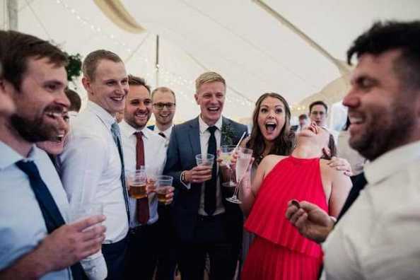 A large group of wedding guests erupt in shock and laughter as Greg Holroyd stuns them with a close-up magic moment inside a Bedfordshire marquee.