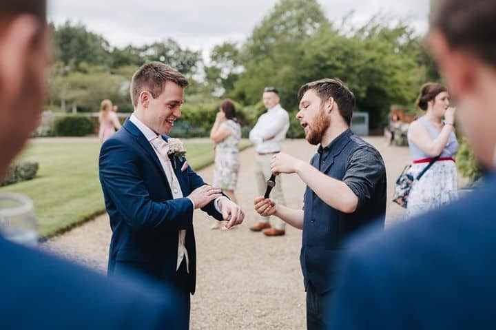 Greg Holroyd performing his signature watch-steal magic trick at a Bedfordshire wedding—groom laughing as the reveal unfolds.